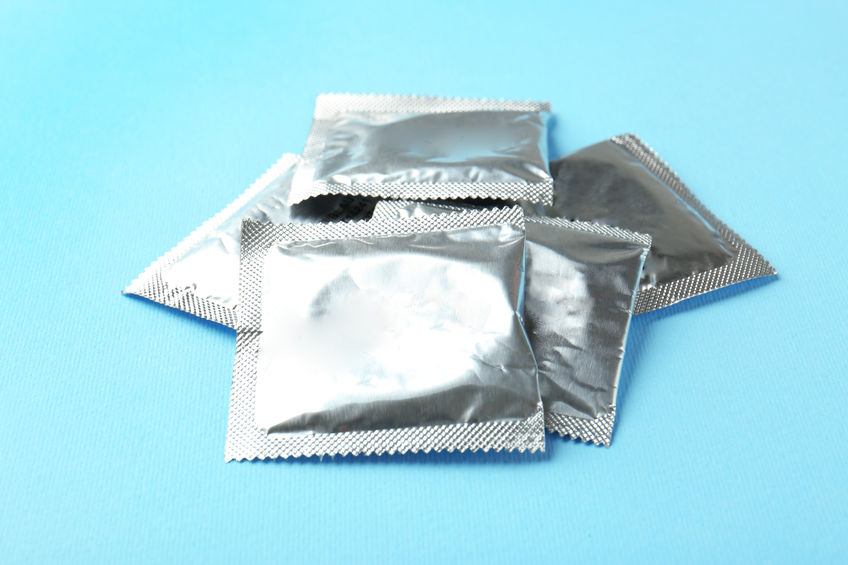 Pile of wrapped condoms on blue background. Safe sex concept