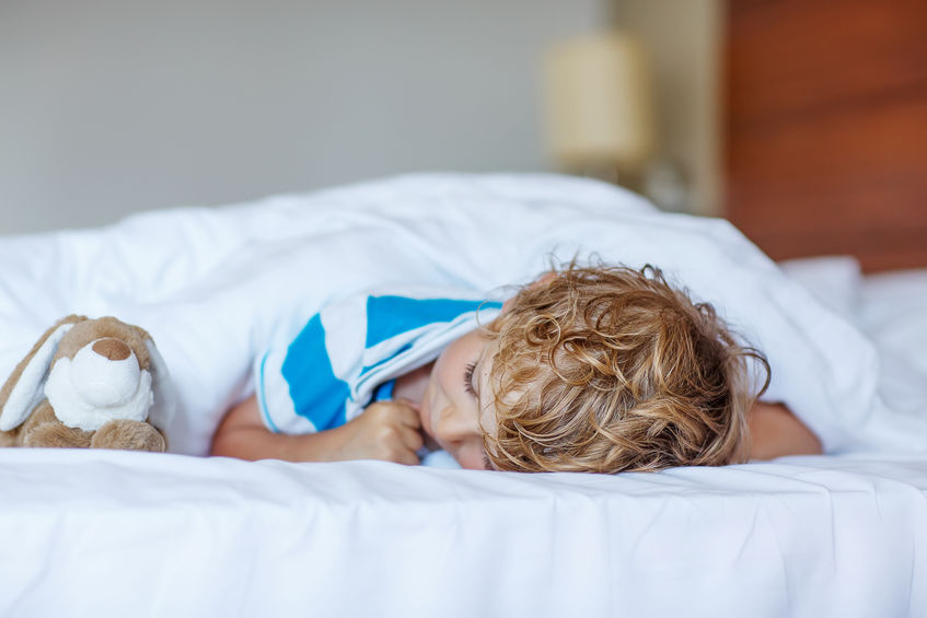 Adorable child sleeping and dreaming in his white bed with toy