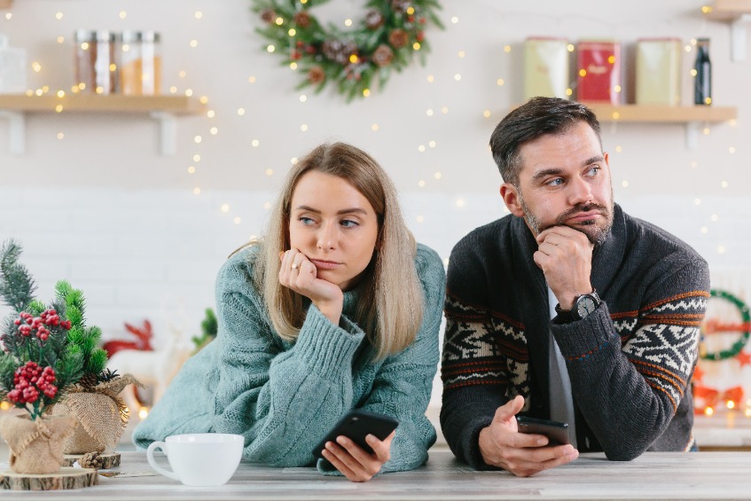 Young family couple quarreled over mobile phone and social networks, man and woman sad during the New Year holidays and Christmas